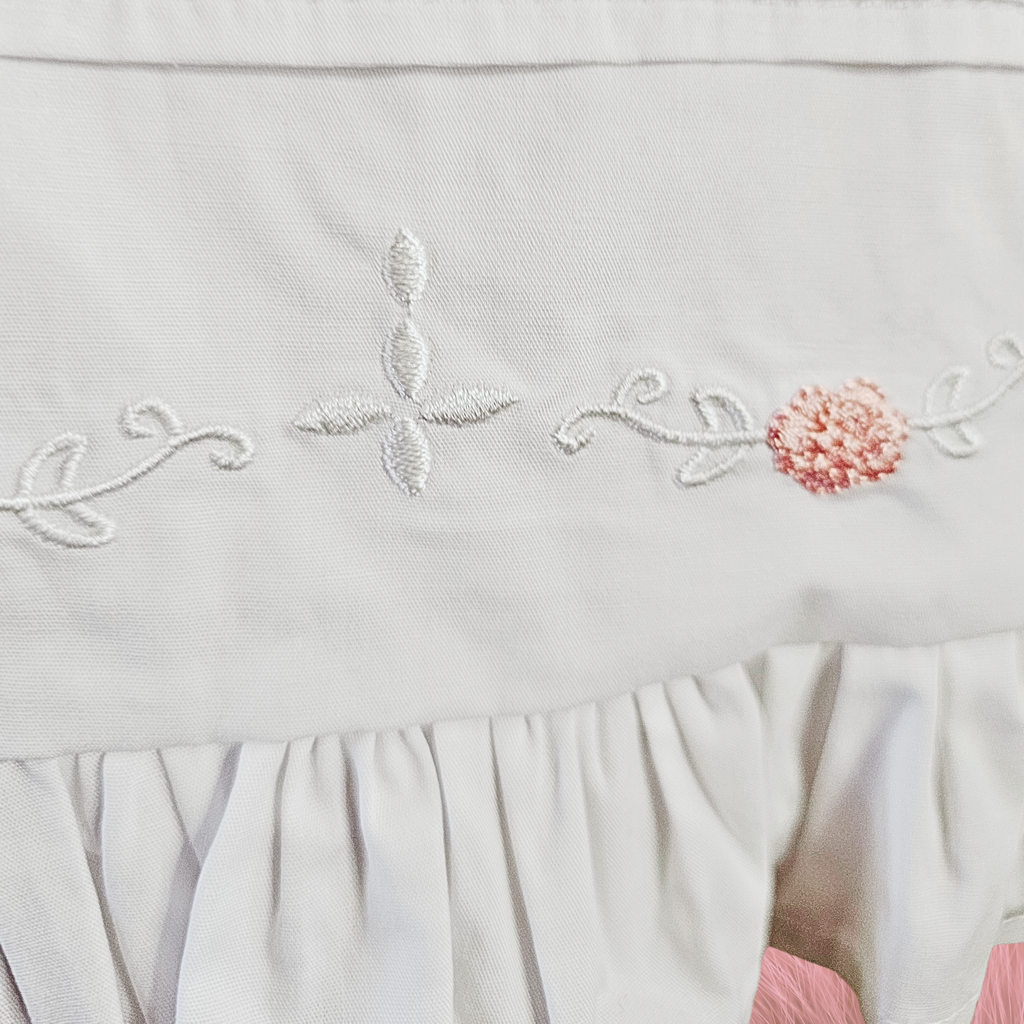 White fabric with floral embroidery and ruffled edge