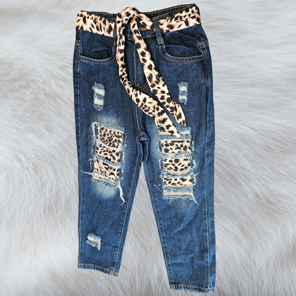 Children's leopard print cutout jeans with a leopard print sash on a fluffy white background. 