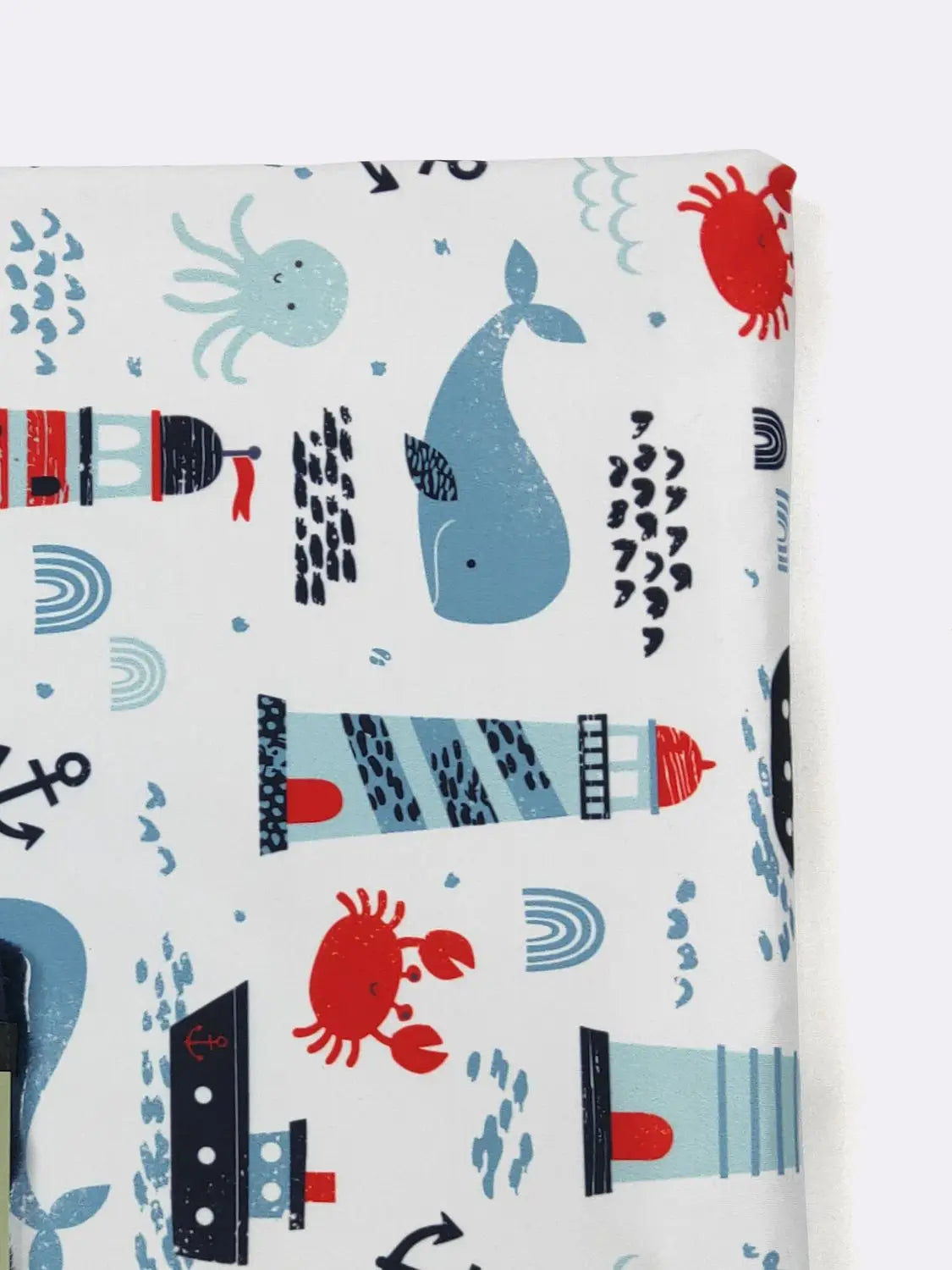 Fabric with nautical-themed pattern featuring whales, crabs, and lighthouses on a white background.