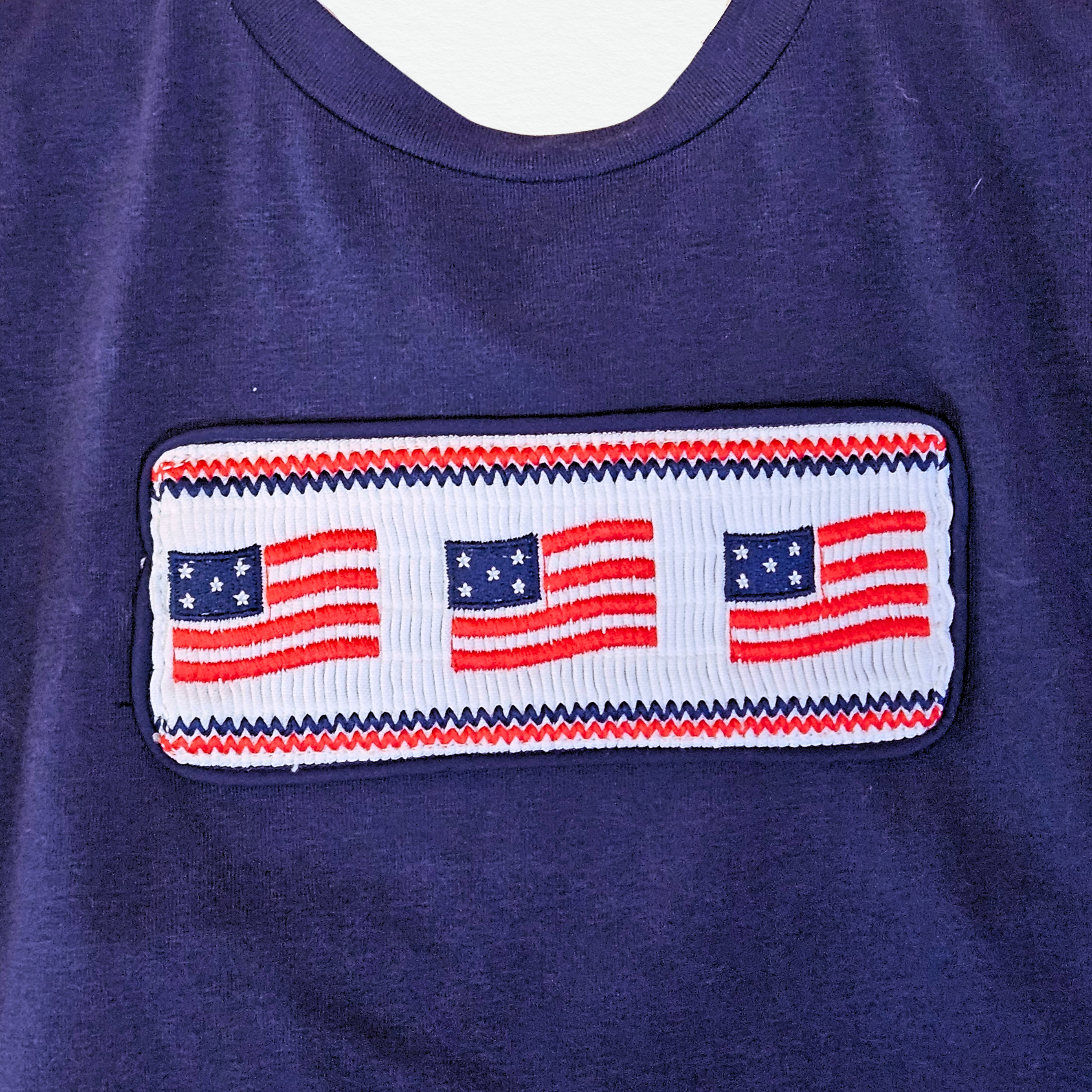 Navy blue shirt with a row of American flags on a white background