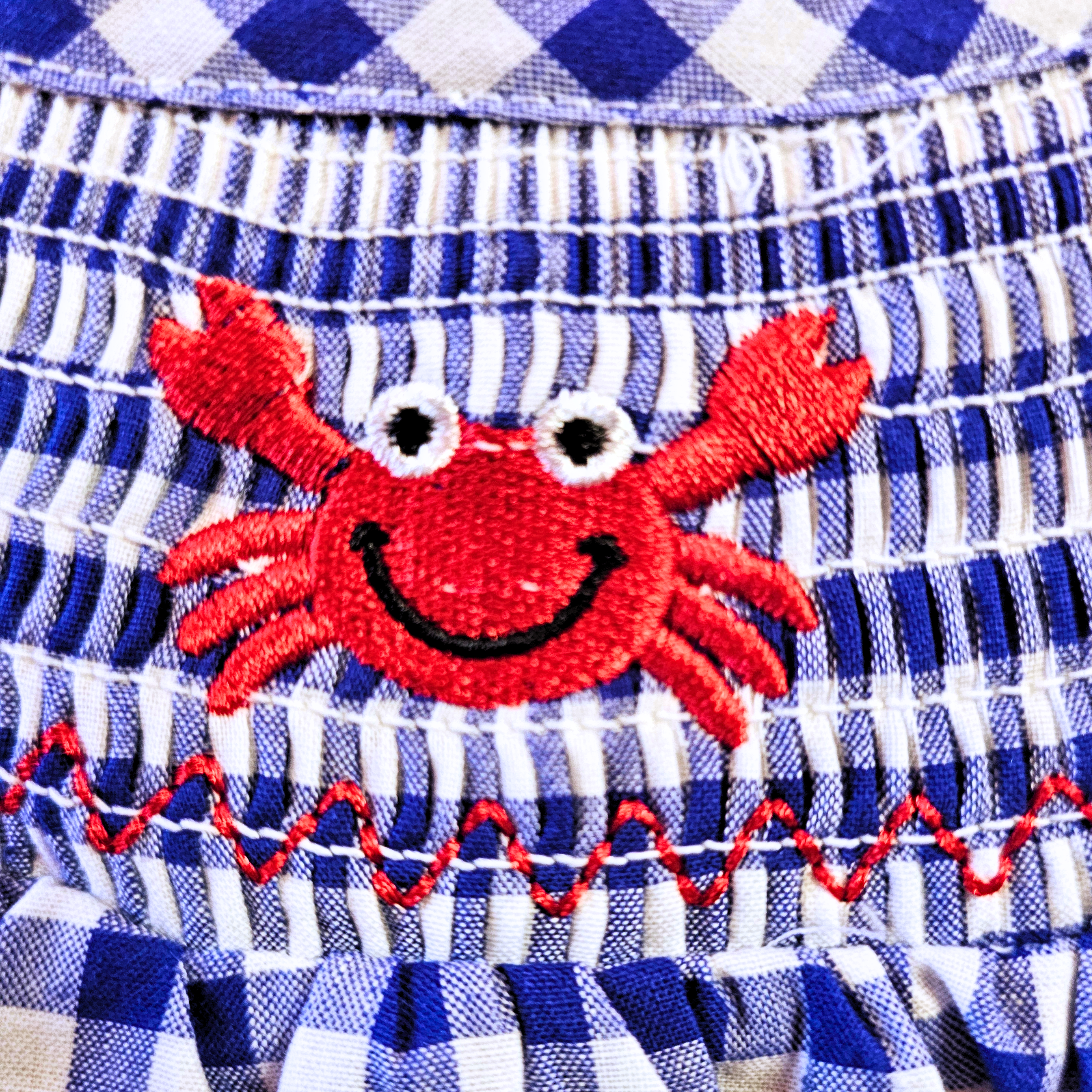 Red embroidered crab on a blue and white checkered fabric background