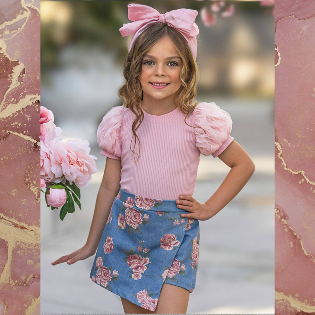 Girl with pink bow wearing a pink puff sleeve top and rose print skort on a pink background