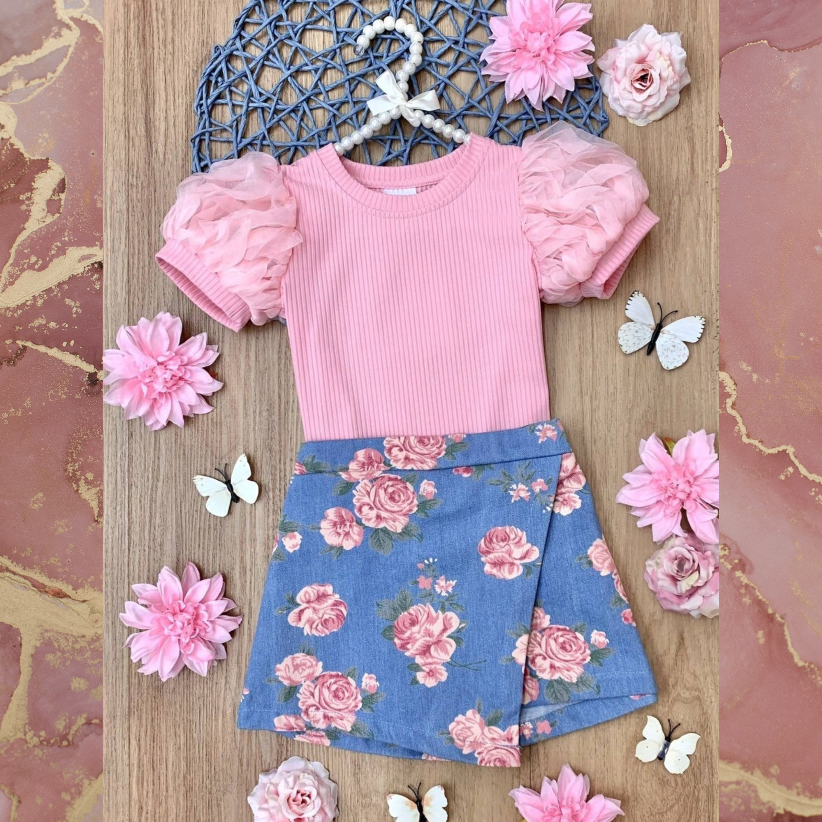 A pink puff sleeve top and rose print skort on a pink background