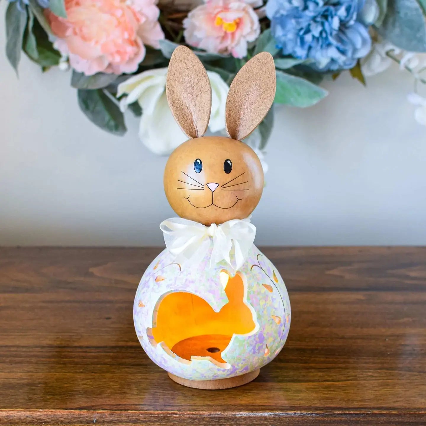Decorative item with a rabbit design on a wooden surface with flowers in the background