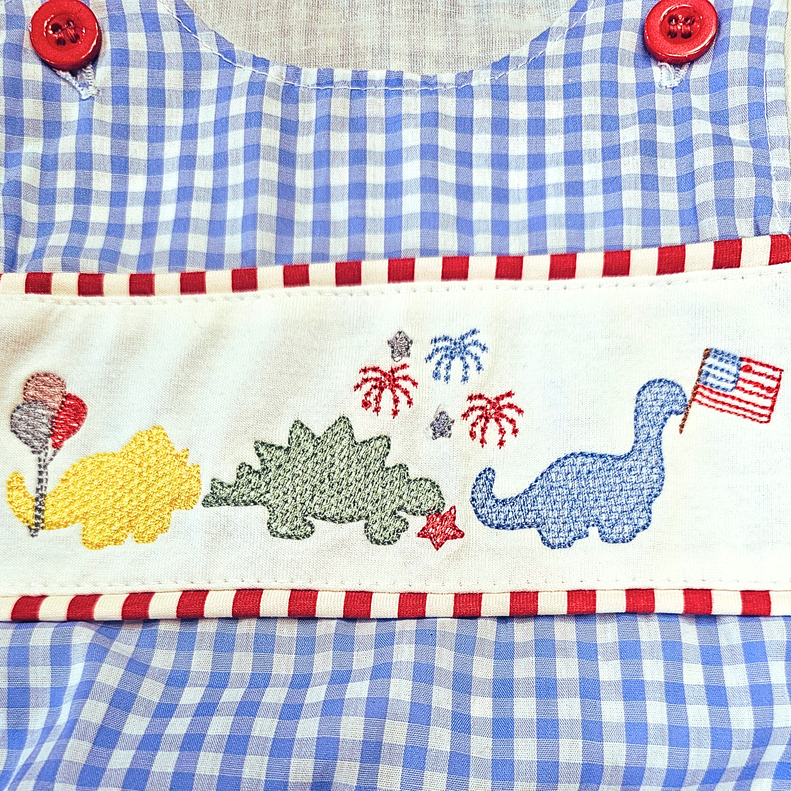 Embroidered fabric with cartoon dinosaurs, balloons, and an American flag on a blue and white checkered background.