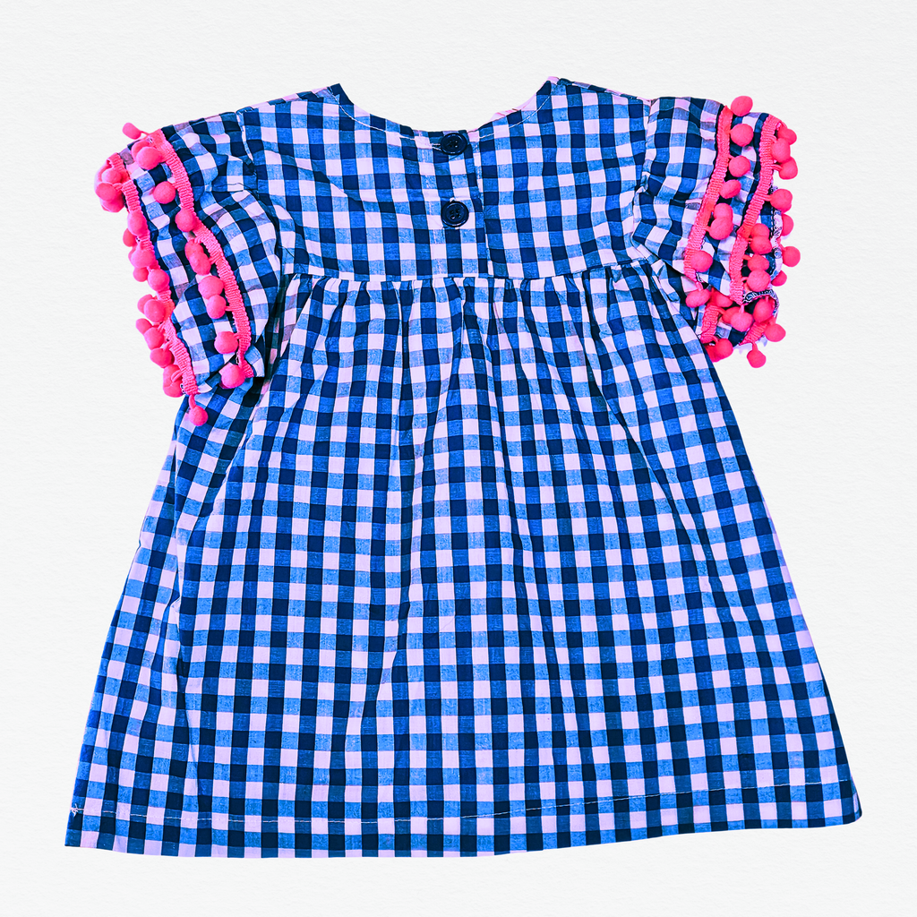 Blue and white checkered dress with pink pom-pom trim on a white background
