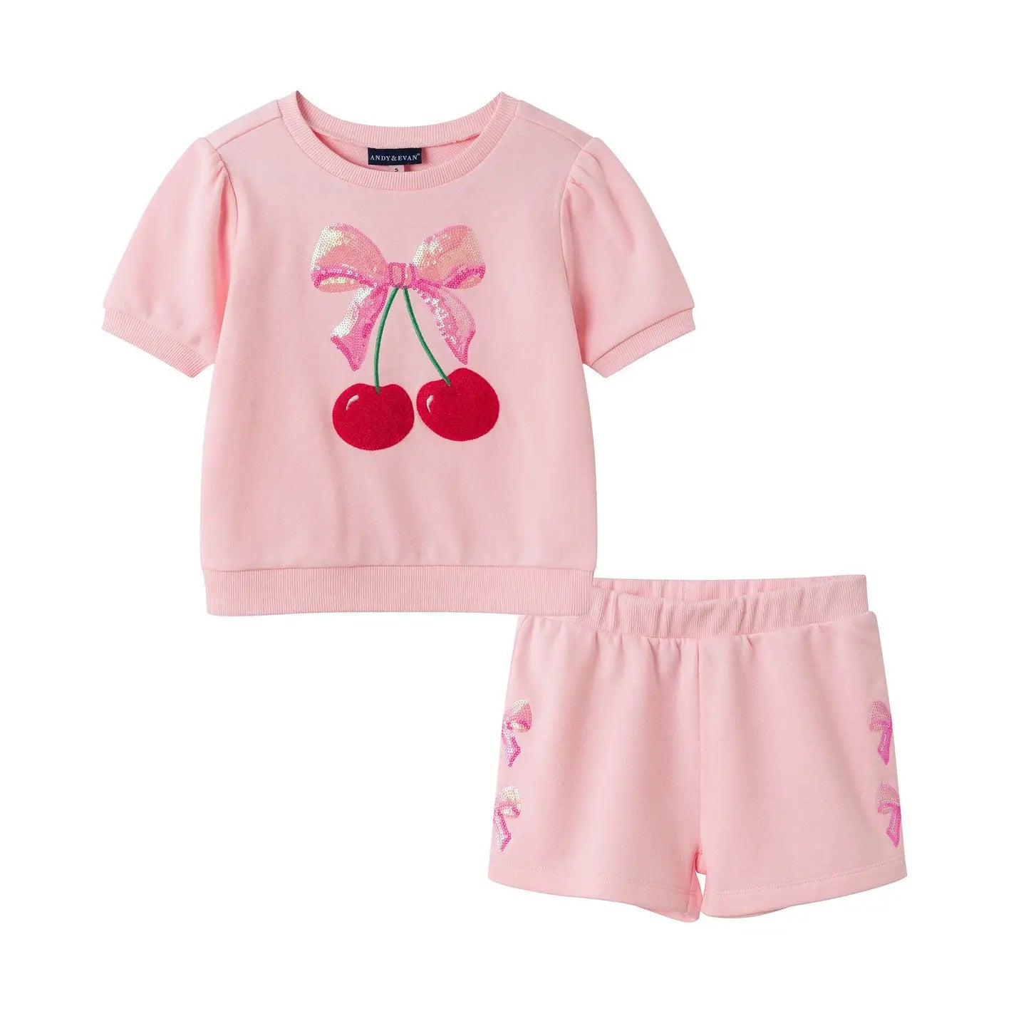 Pink children's outfit with cherry and bow design on a white background