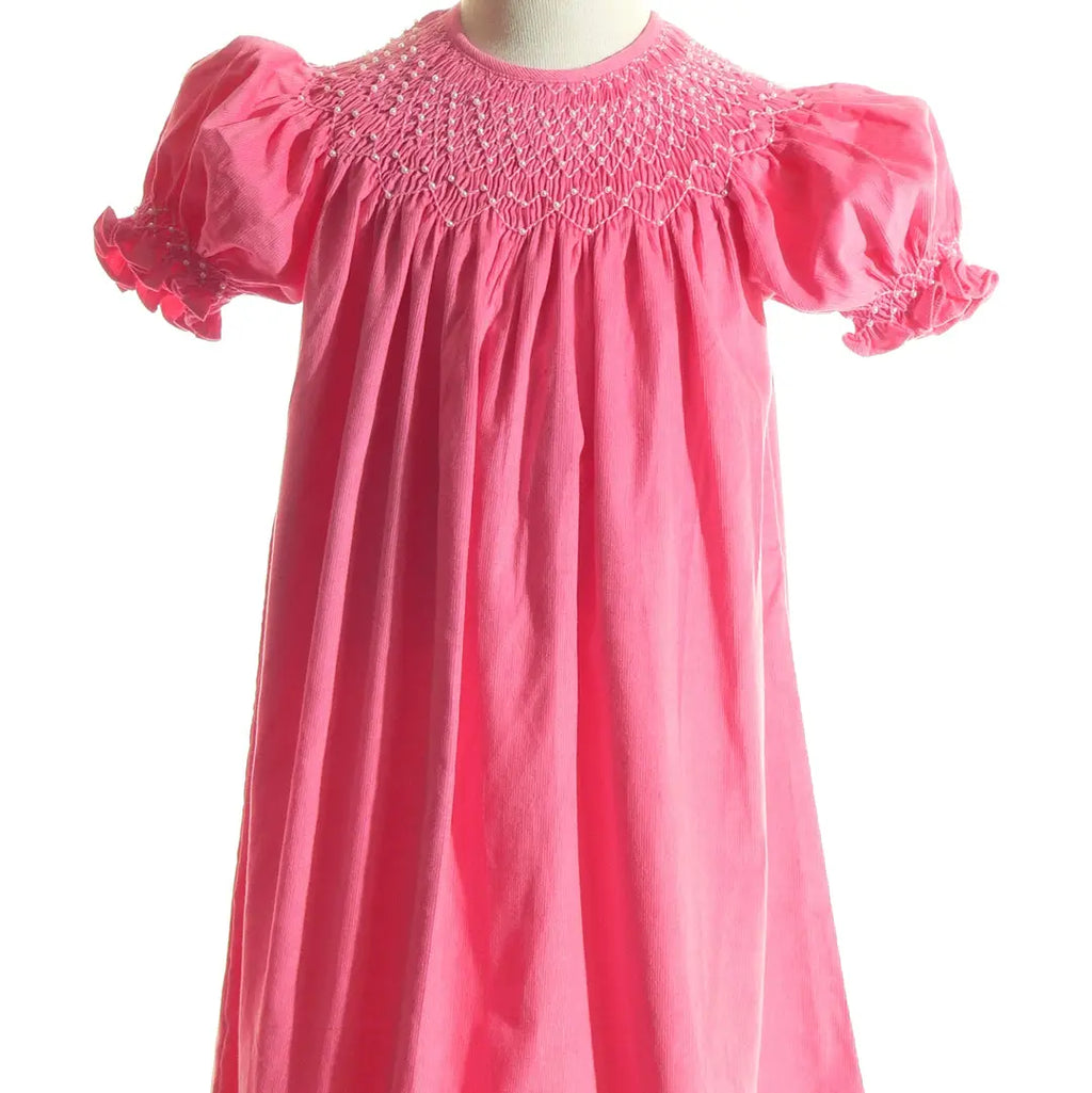 Pink dress with smocked neckline and short sleeves on a white background