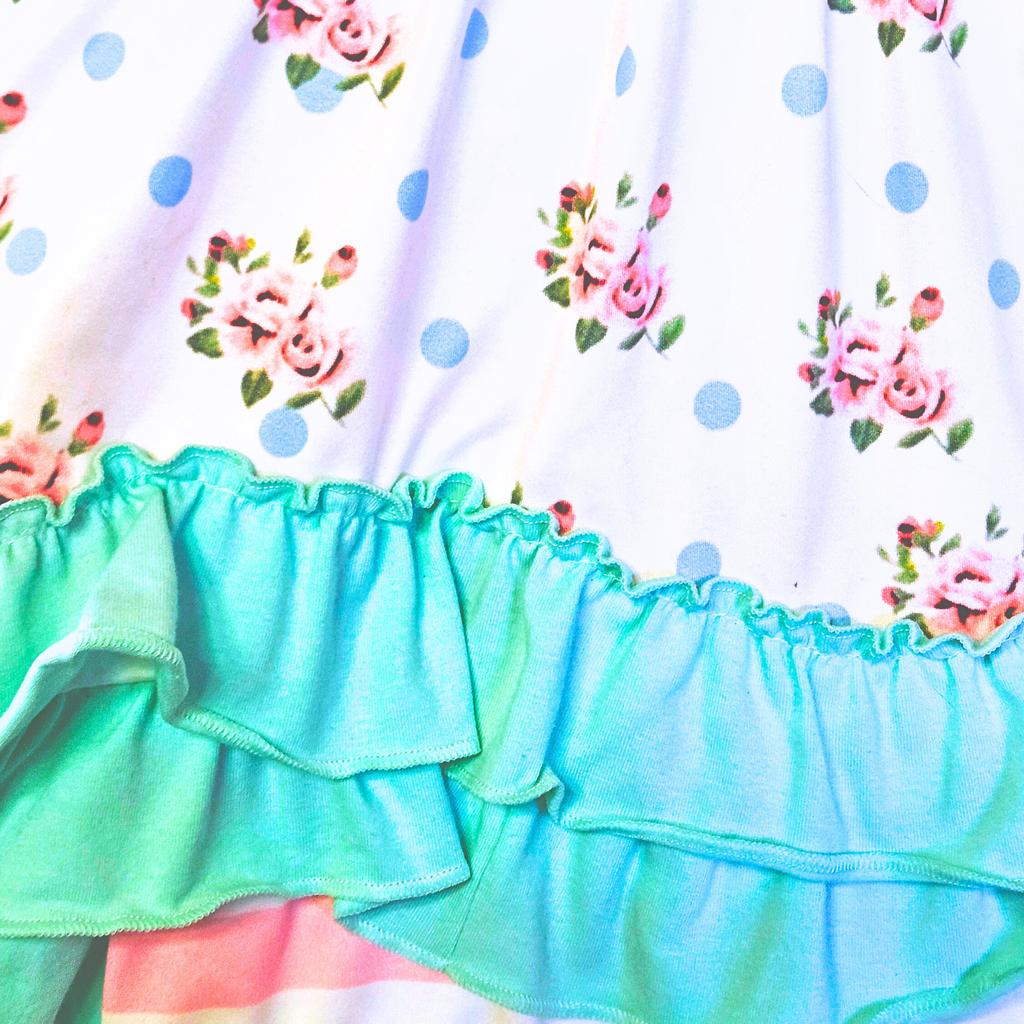 Close-up of a colorful dress with floral patterns and ruffled hem on a white background.
