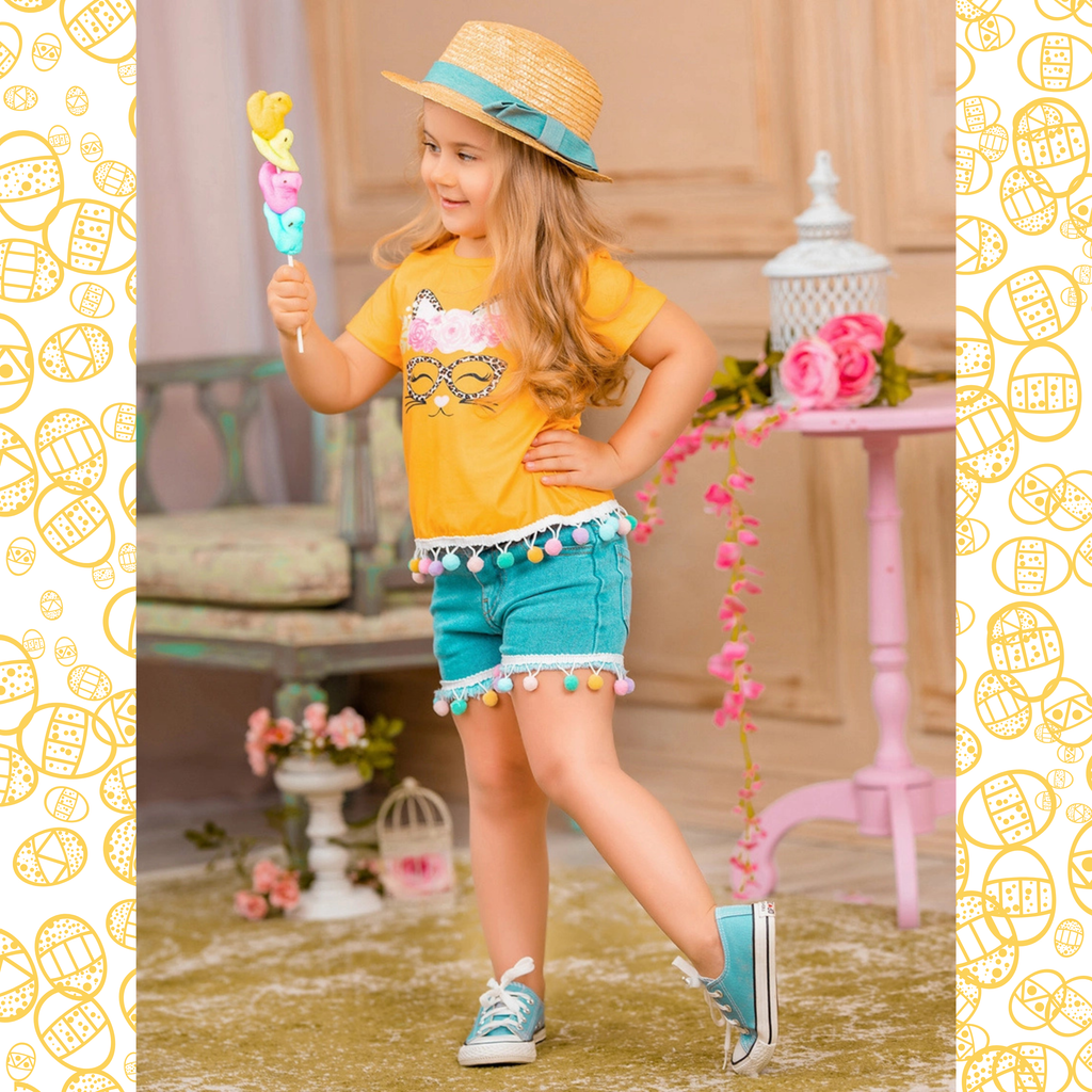 Young girl in yellow shirt and blue shorts holding a colorful ice cream cone in a decorative setting.
