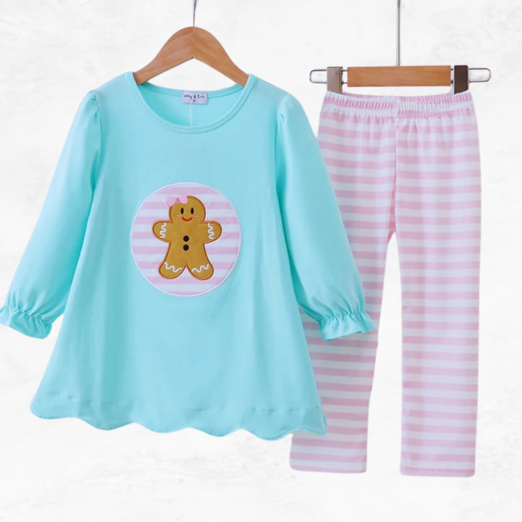 Children's pant set with a blue top and pink striped pants on hangers against a white background.