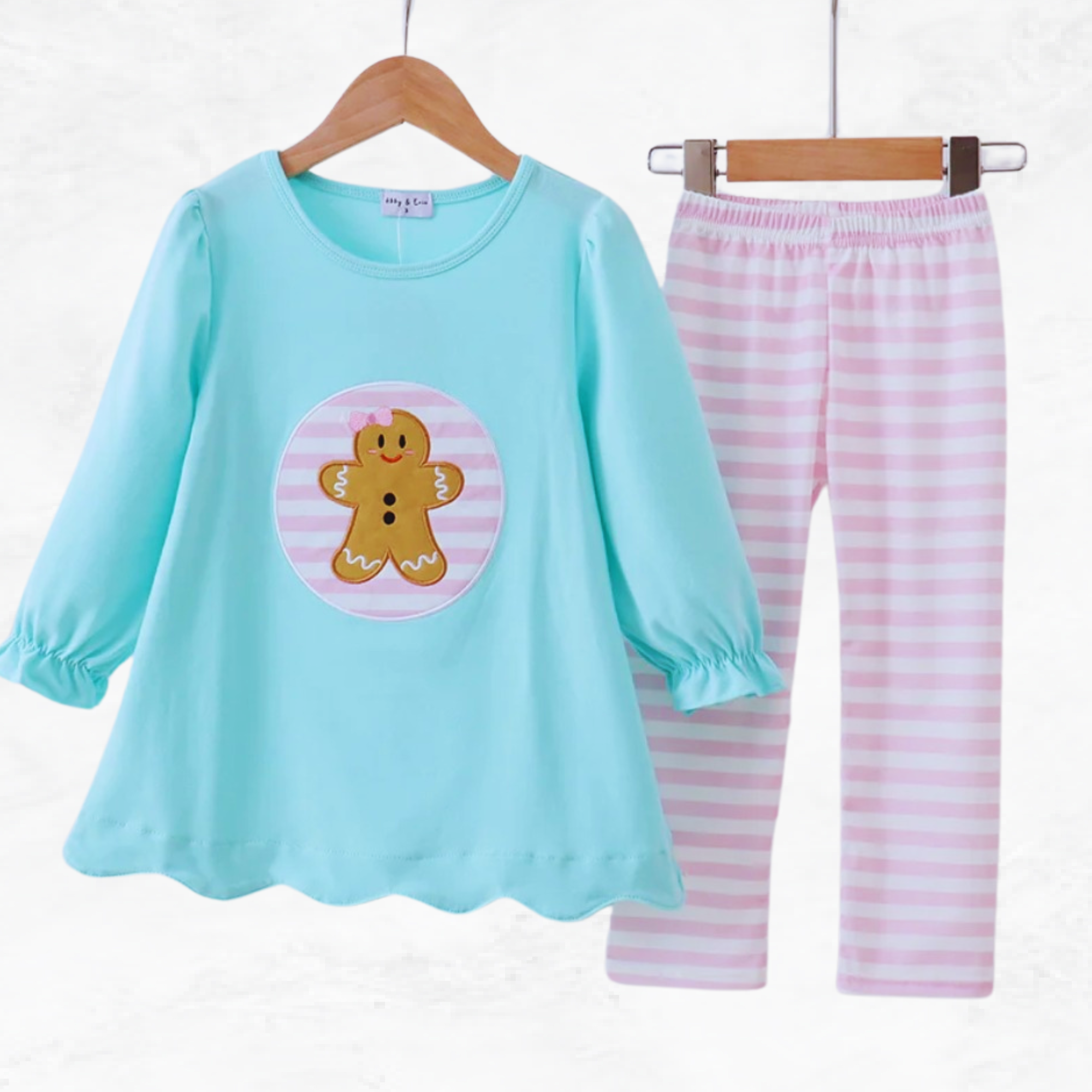 Children's pant set with a blue top and pink striped pants on hangers against a white background.