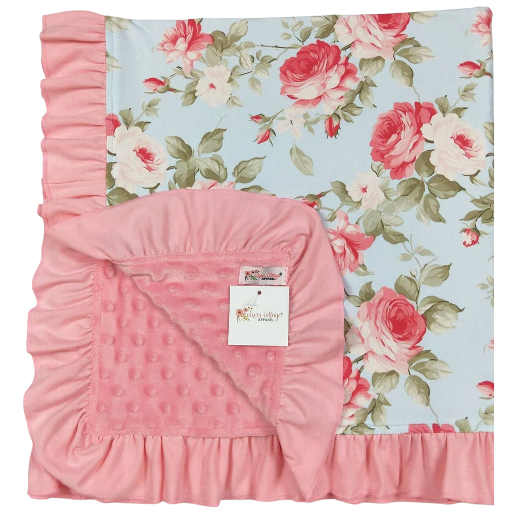 Pink floral crib set with a floral patterned sheet and pink ruffled blanket on a white background.
