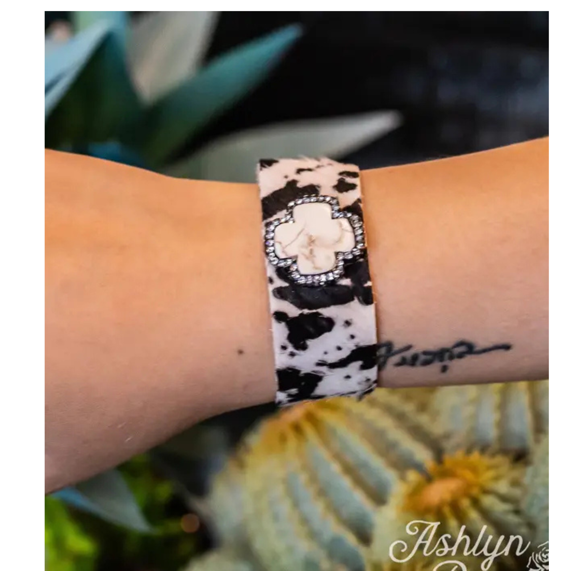 Close-up of a wrist wearing a bracelet with a floral design, set against a blurred natural background.