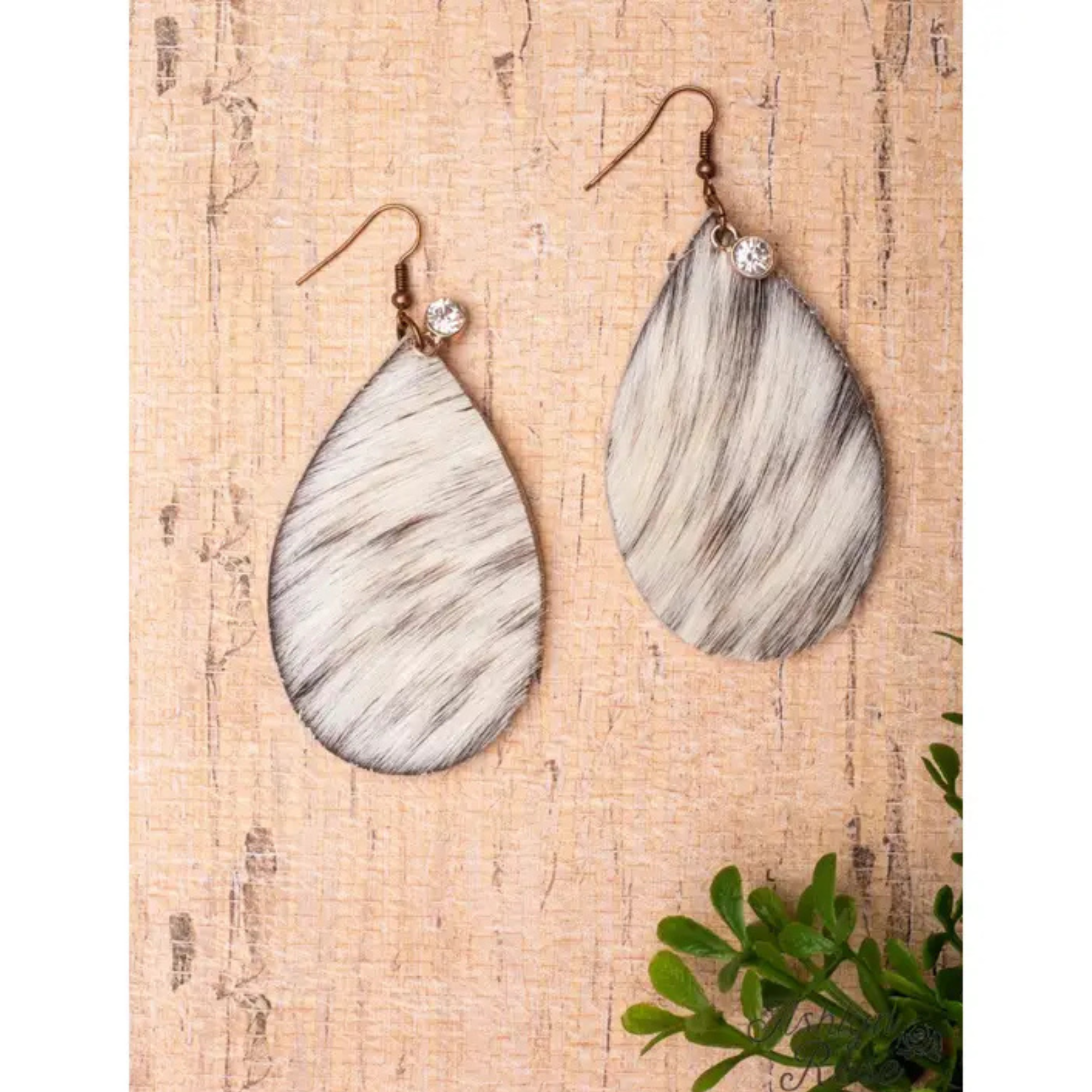 Teardrop-shaped earrings with marble pattern on a wooden surface