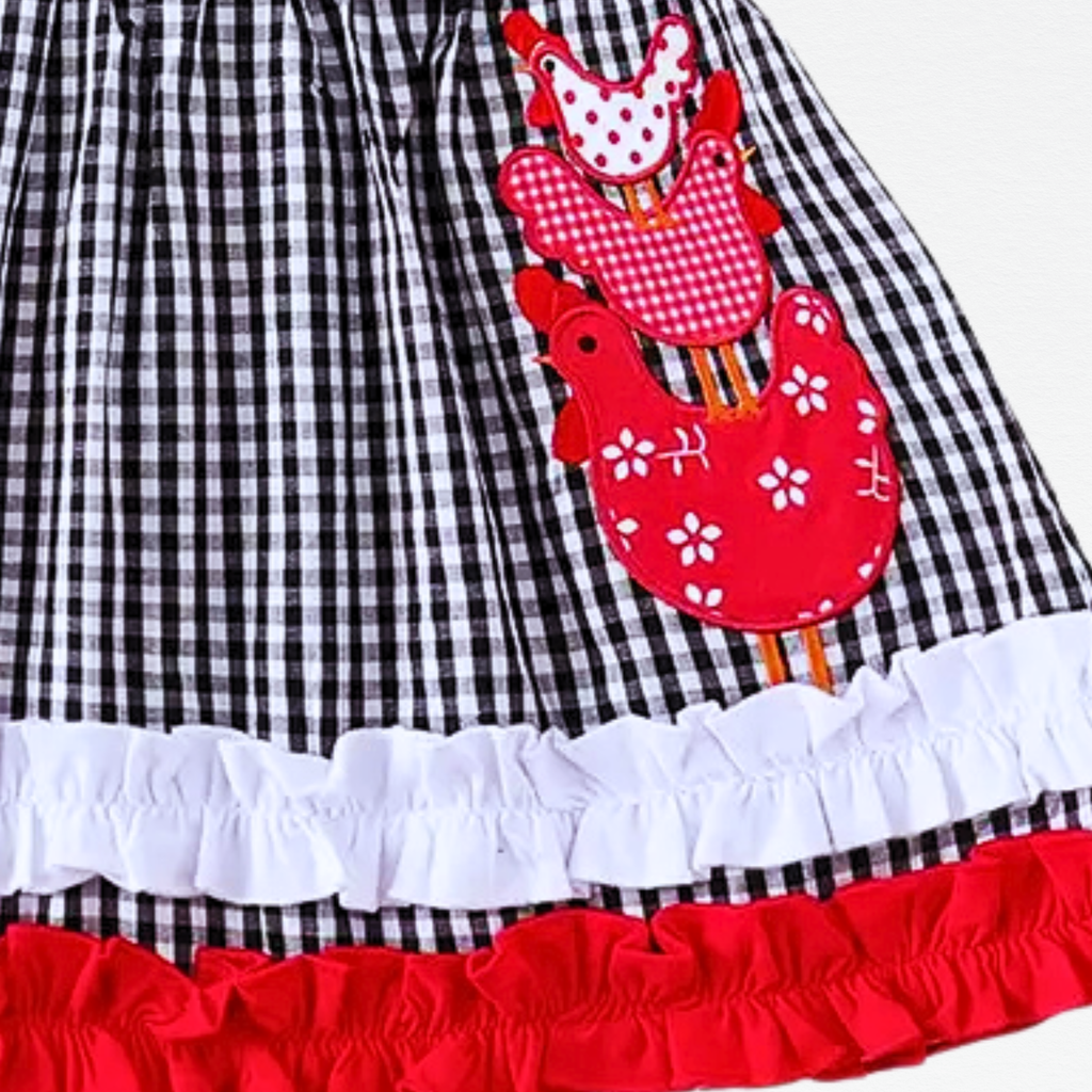 Black and white checkered dress with red rooster appliqués on a white background