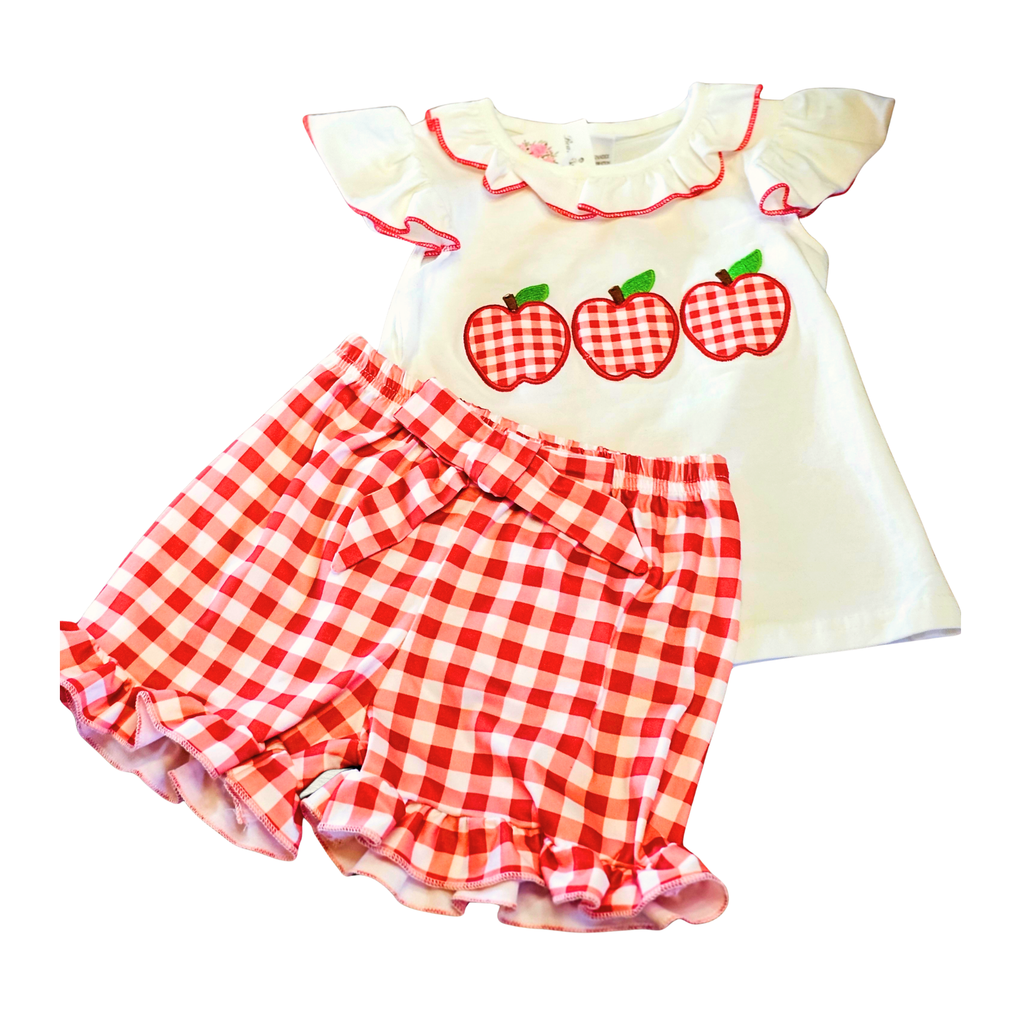 Children's outfit with a white top and red checkered shorts featuring apple designs on a white background.