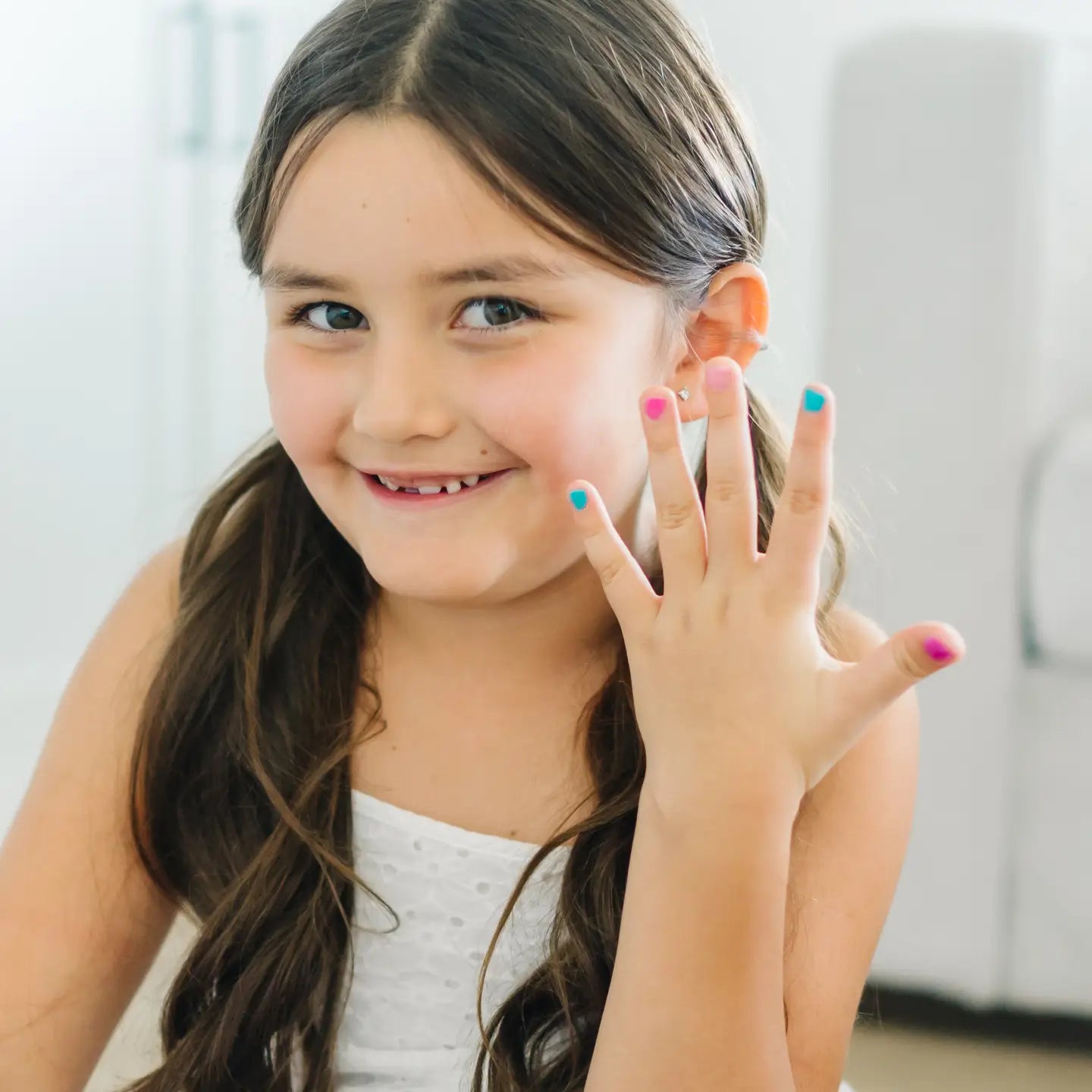 Young girl showing off her painted nails with a smile.