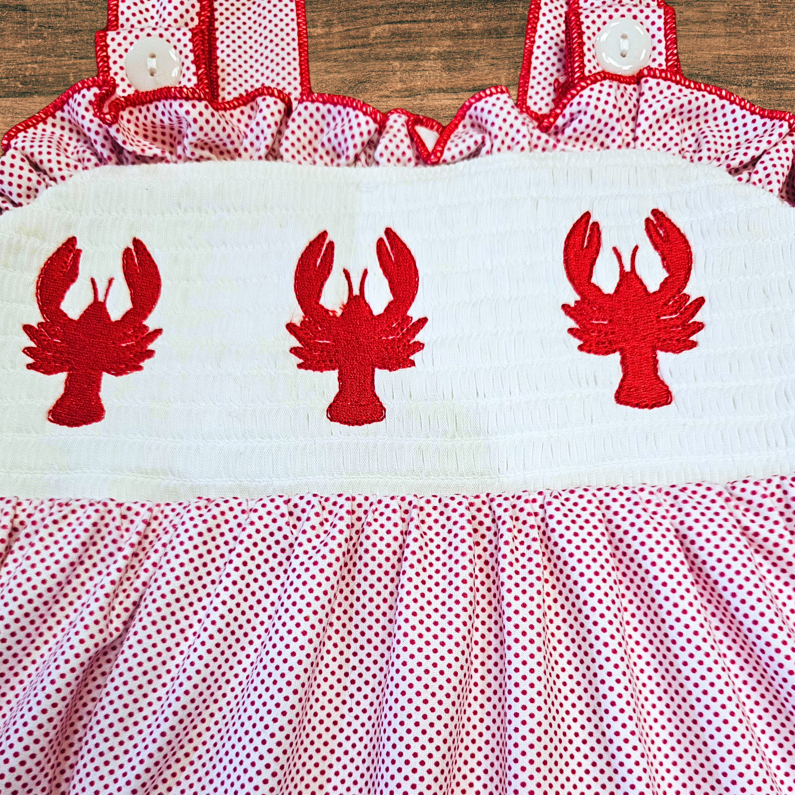 Children's dress with red lobster designs on a wooden background