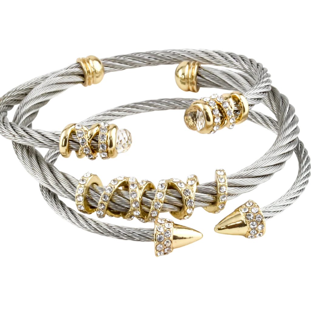 Stack of silver and gold bracelets with beaded and spike-like ends on a white background