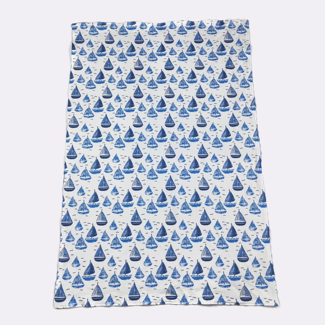 Blanket with blue sailboat pattern on a white background