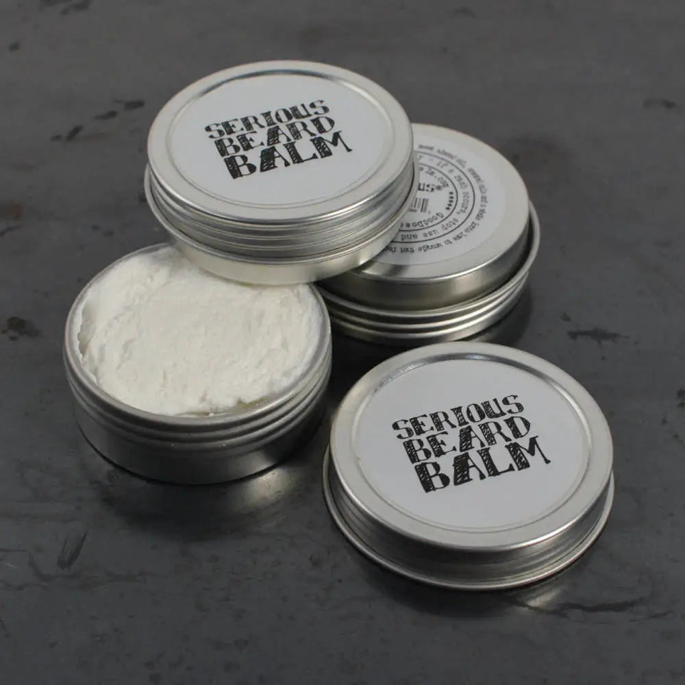Three tins of 'Serious Beard Balm' on a dark surface