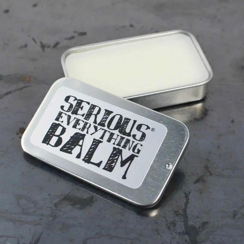 Metal tin labeled 'Serious Everything Balm' on a textured surface