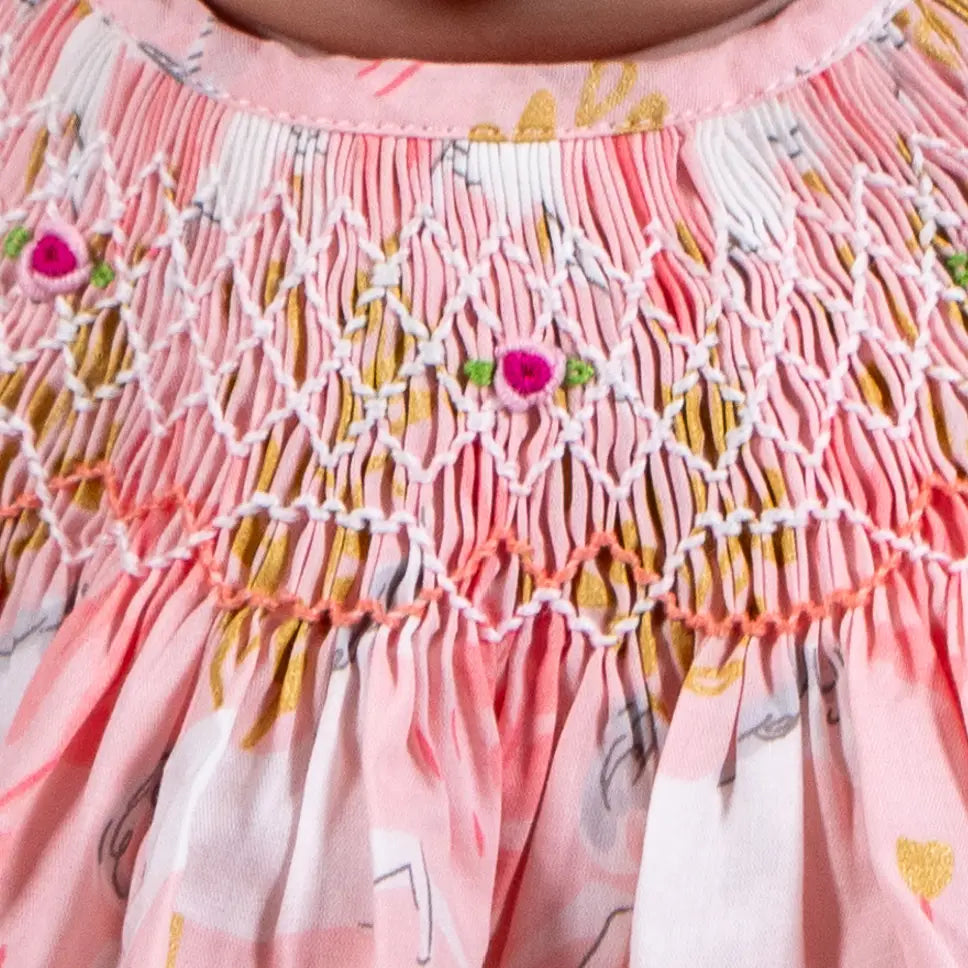 Close-up of a pink dress with floral patterns and embroidery details.