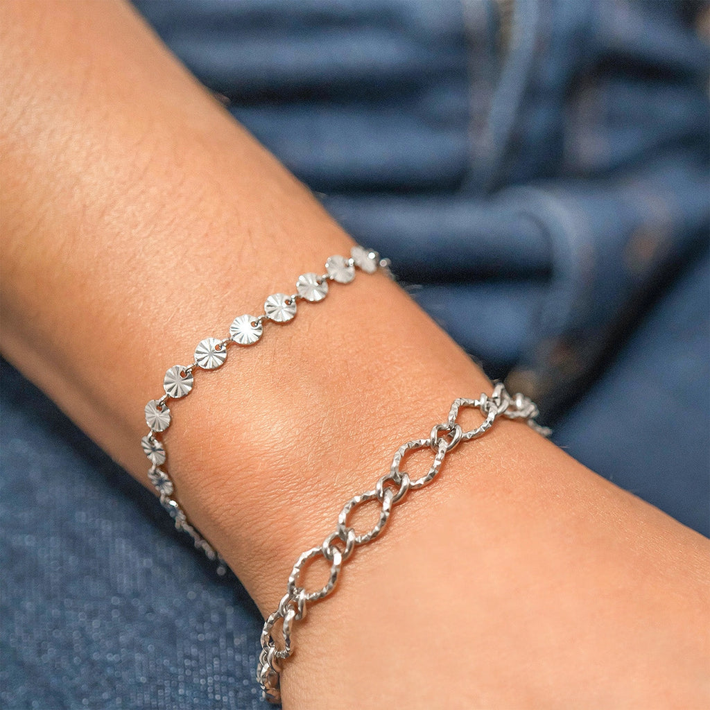 Silver bracelet on a wrist with a blue fabric background