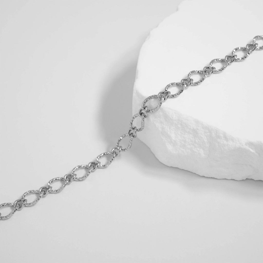 Silver chain bracelet on a white stone surface