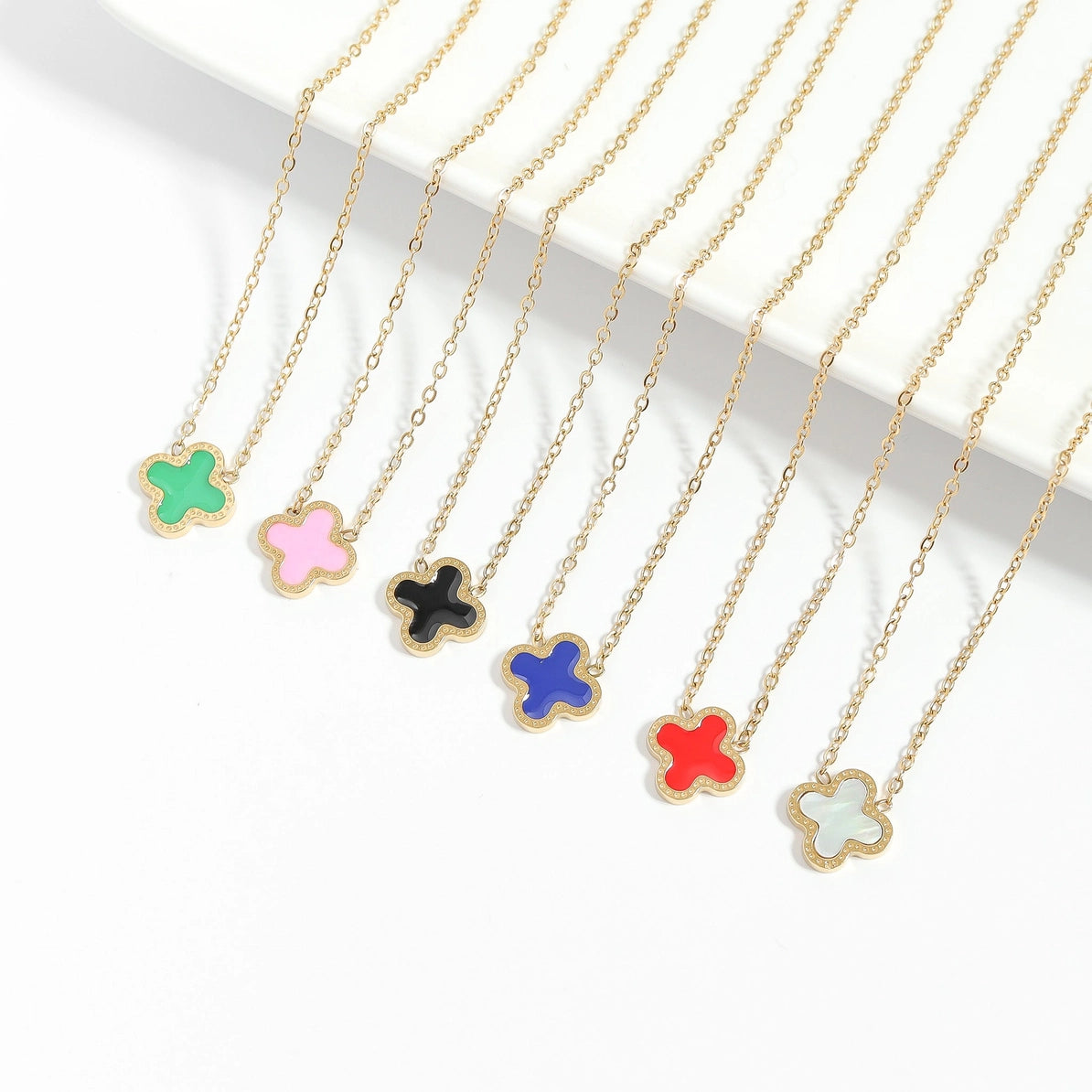 Colorful flower-shaped pendants on gold chains against a white background