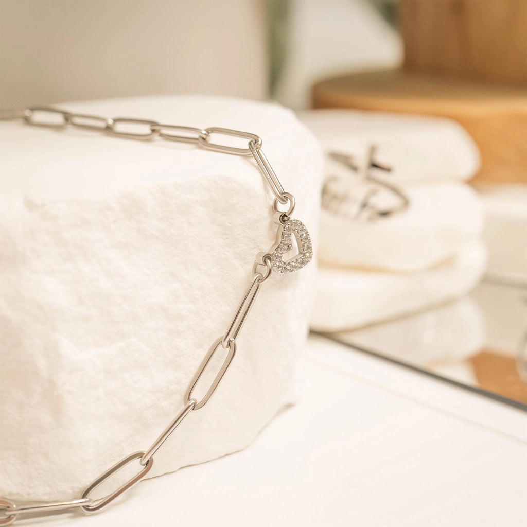 Silver chain bracelet on a white surface with a blurred background