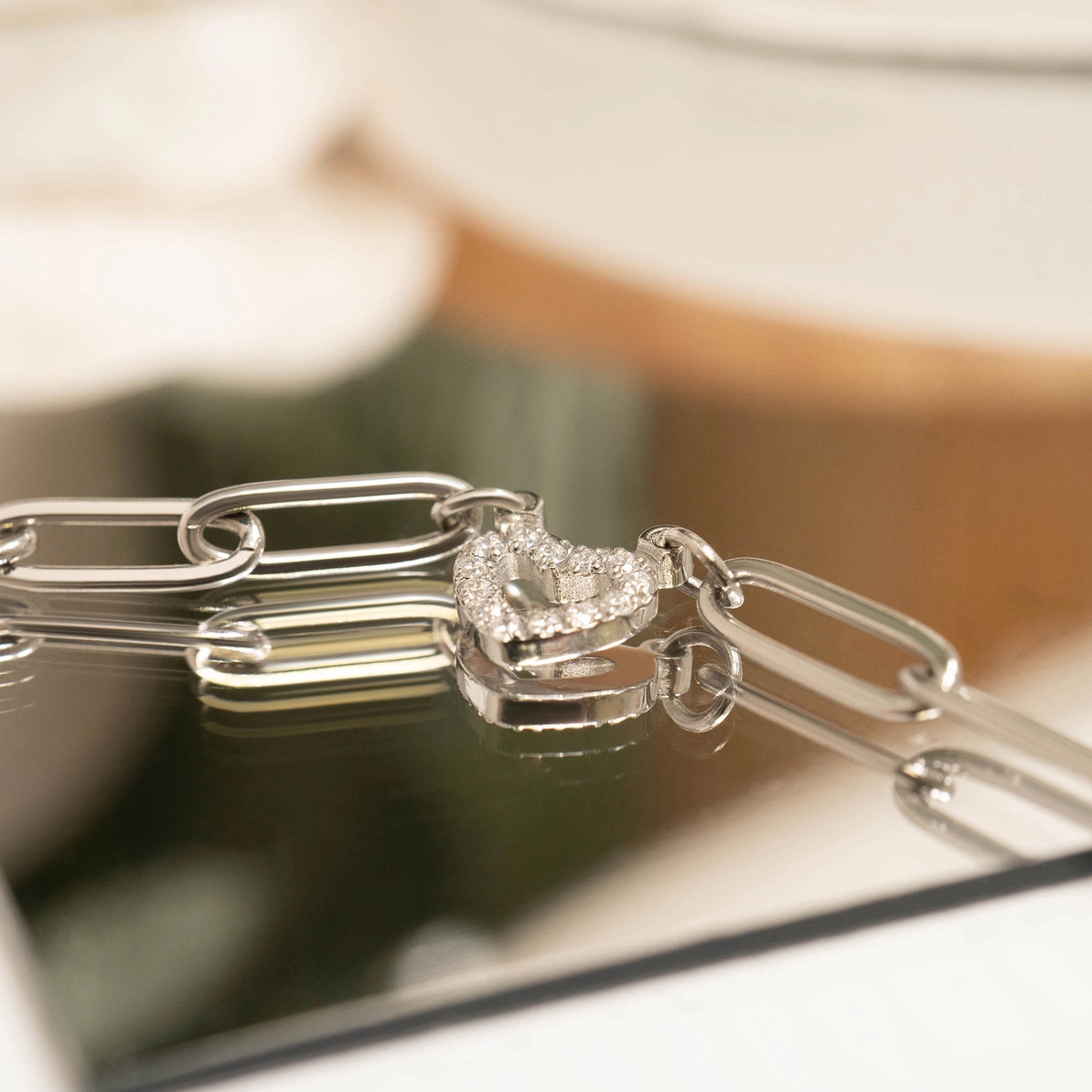 Silver chain with a heart-shaped pendant on a reflective surface