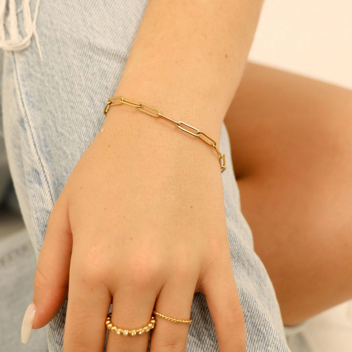 Gold bracelet and ring on a person's wrist with a blurred background