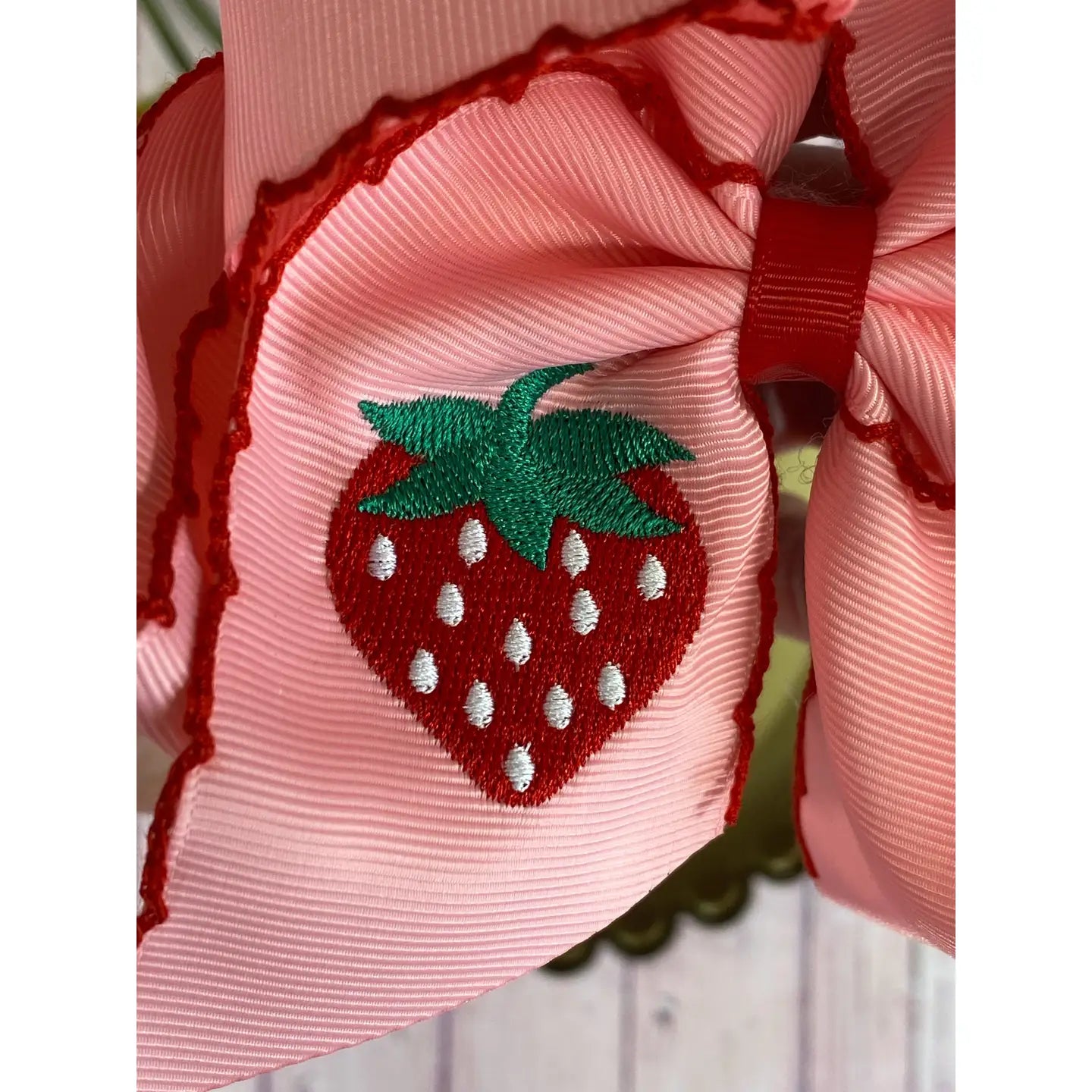 Pink hair bow with a strawberry design on a blurred background