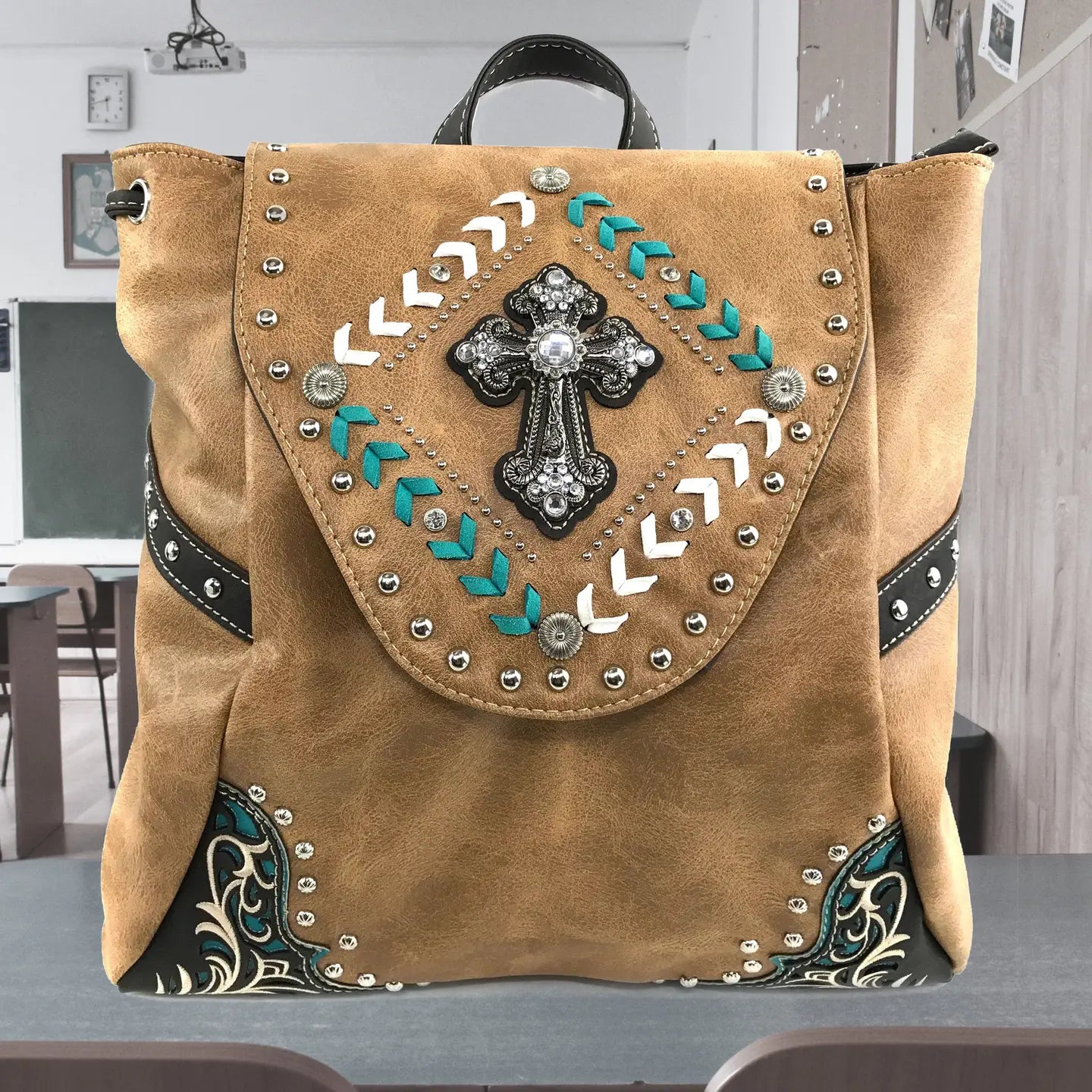 Brown leather backpack with decorative cross and patterns on a table.