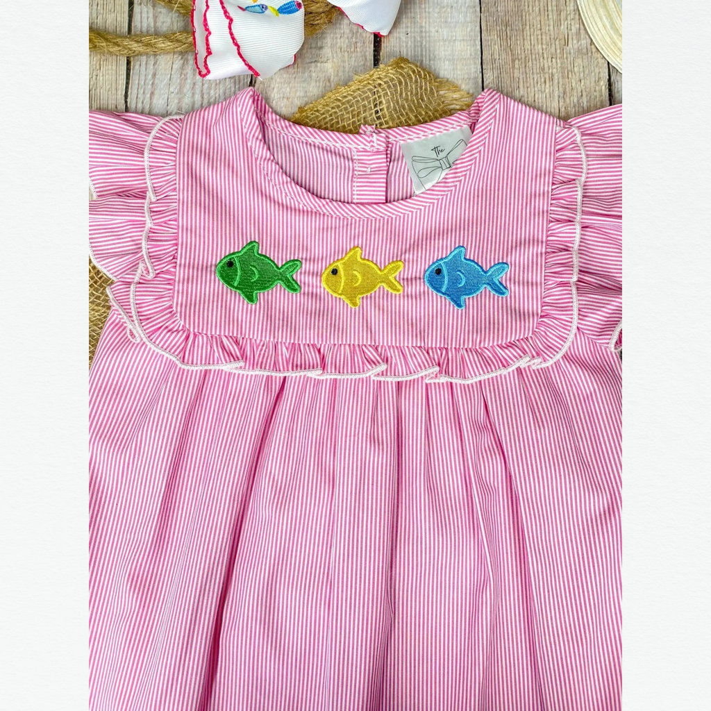 Pink dress with fish embroidery on a wooden surface