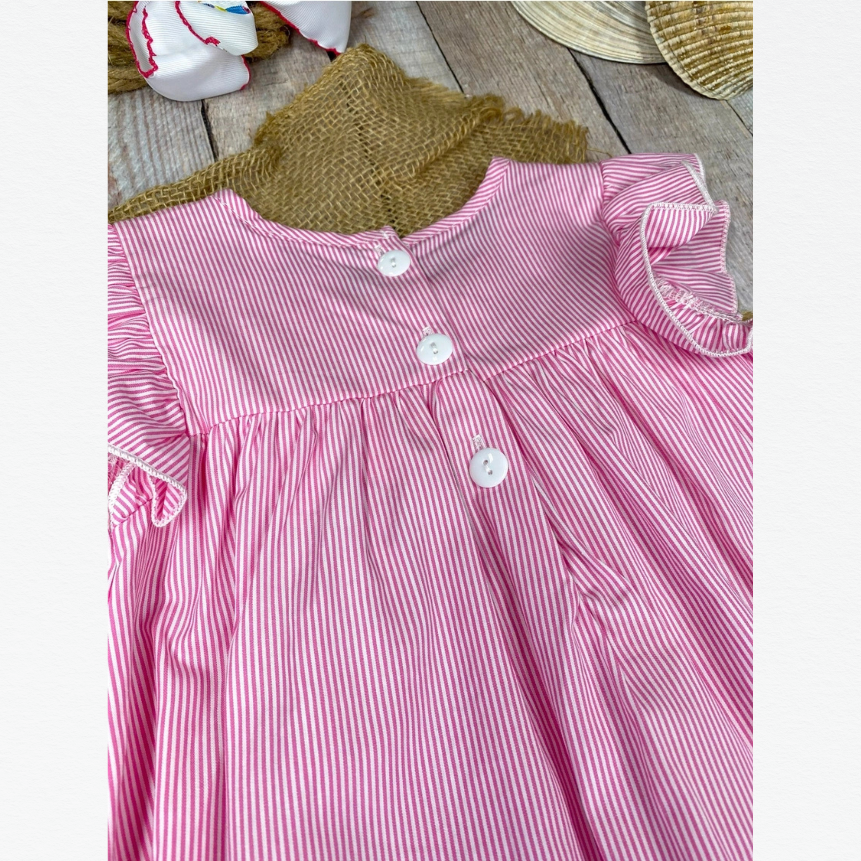 Pink and white striped dress with a green collar on a wooden surface