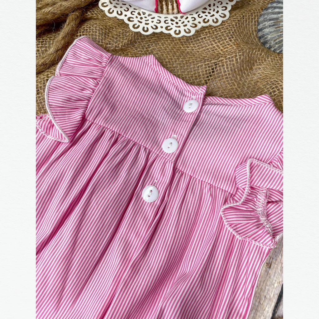 Pink and white striped dress with ruffled sleeves on a textured surface