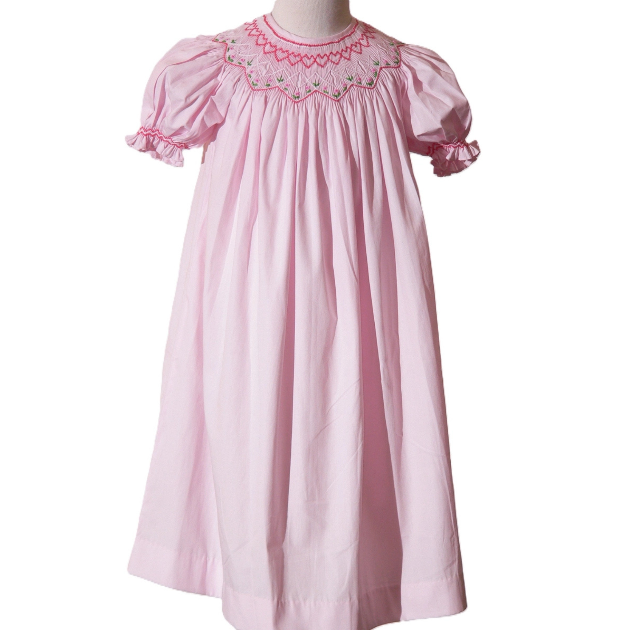 Pink dress with embroidered details on a white background