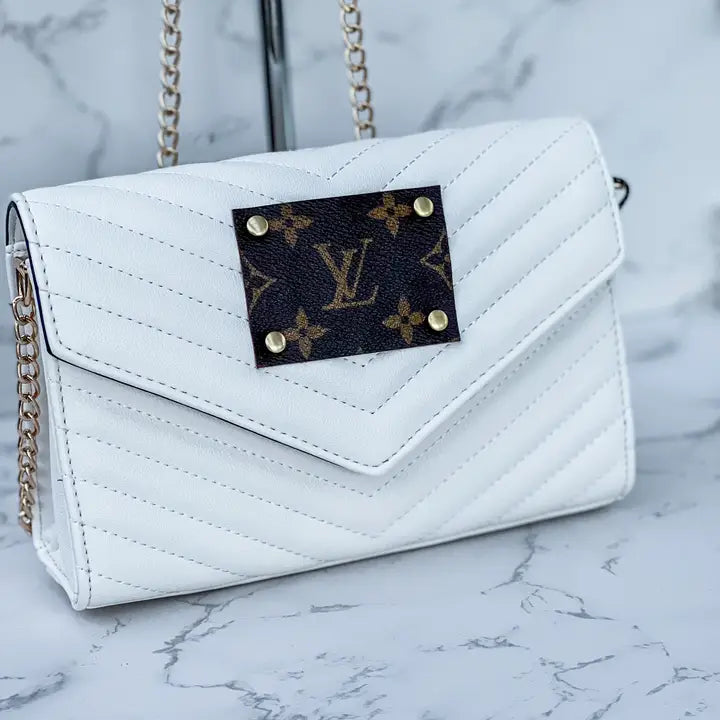 White quilted handbag with a brand patch on a marble surface