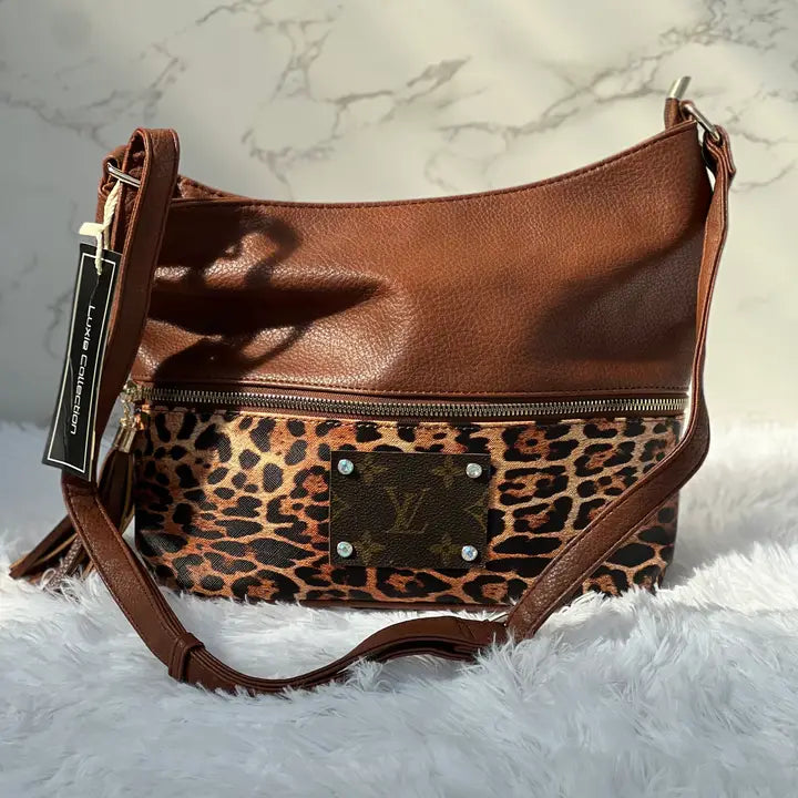 Brown leather handbag with leopard print section on a white fur surface