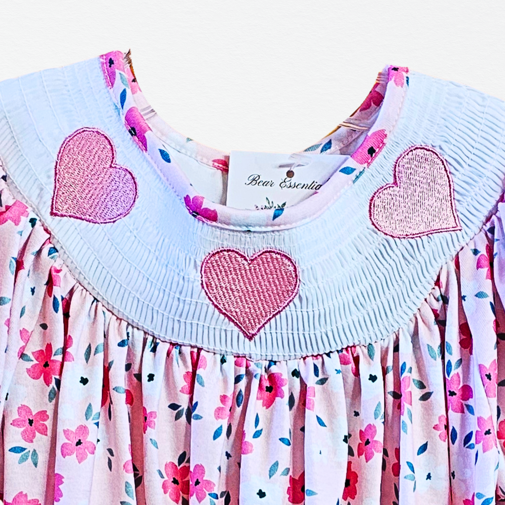 Children's dress with heart designs and floral pattern on a white background