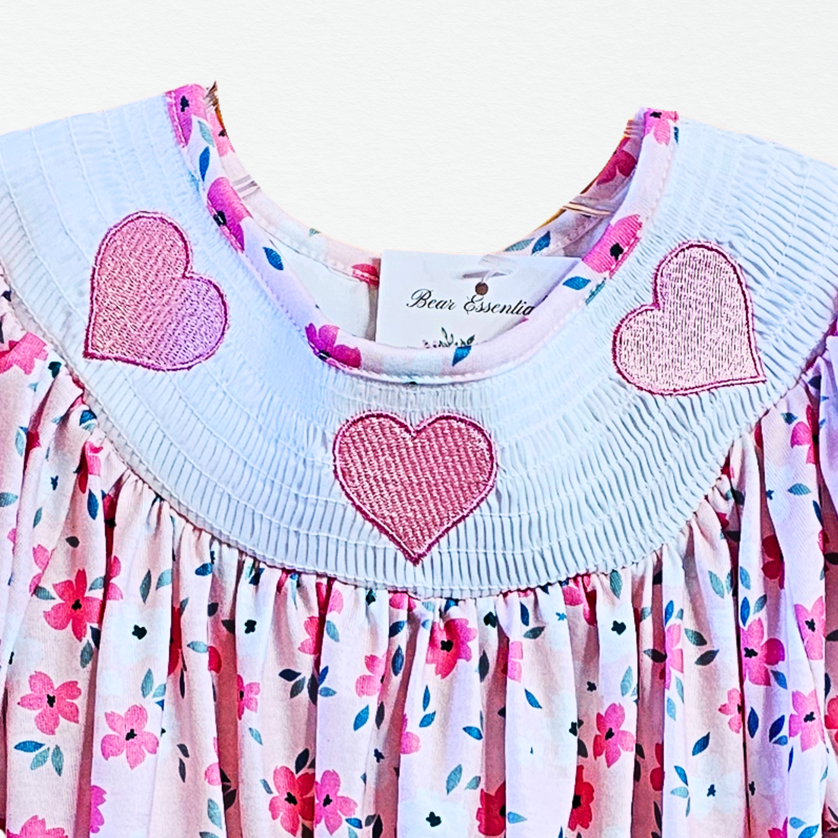 Children's dress with heart designs and floral pattern on a white background