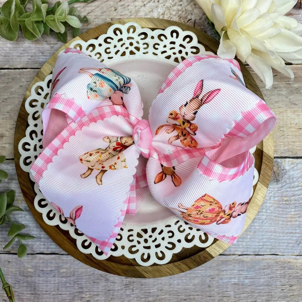 Large decorative bow with pink and white checkered pattern on a wooden plate.