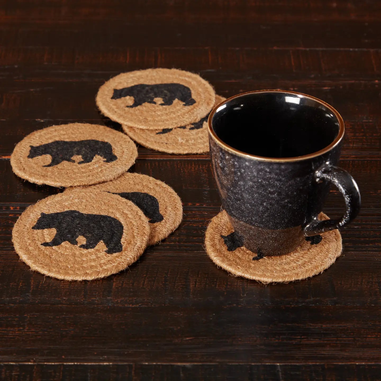 Set of coasters with bear design on a wooden surface with a black mug.