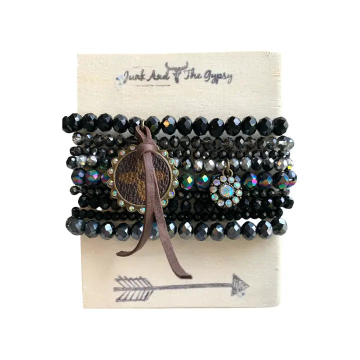 Set of black beaded bracelets with a leather strap on a branded card.