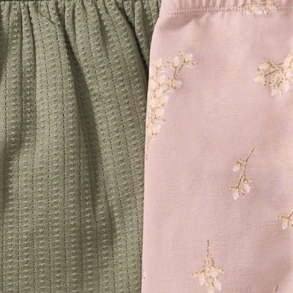 Close-up of textured green fabric and floral-patterned pink fabric.