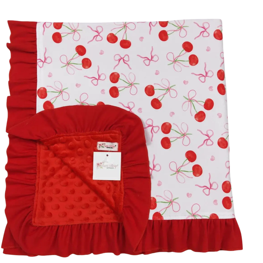 Red baby blanket with cherry pattern on a white background