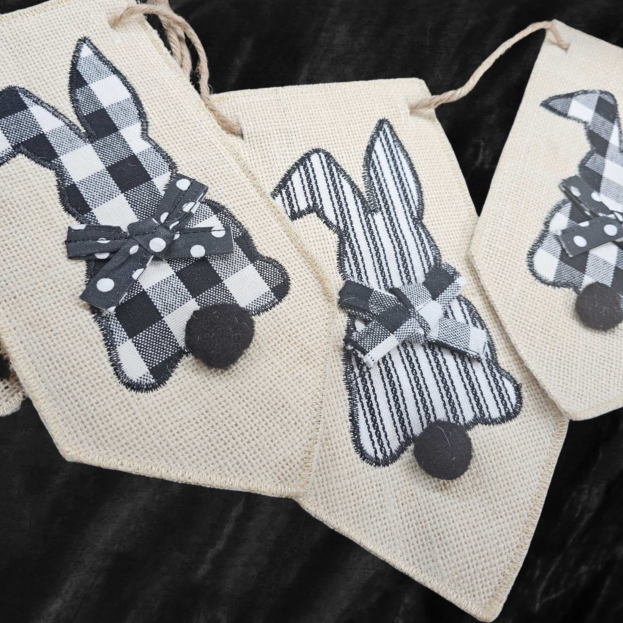 Decorative bunny-shaped bunting with black and white checkered and striped patterns on a dark background.